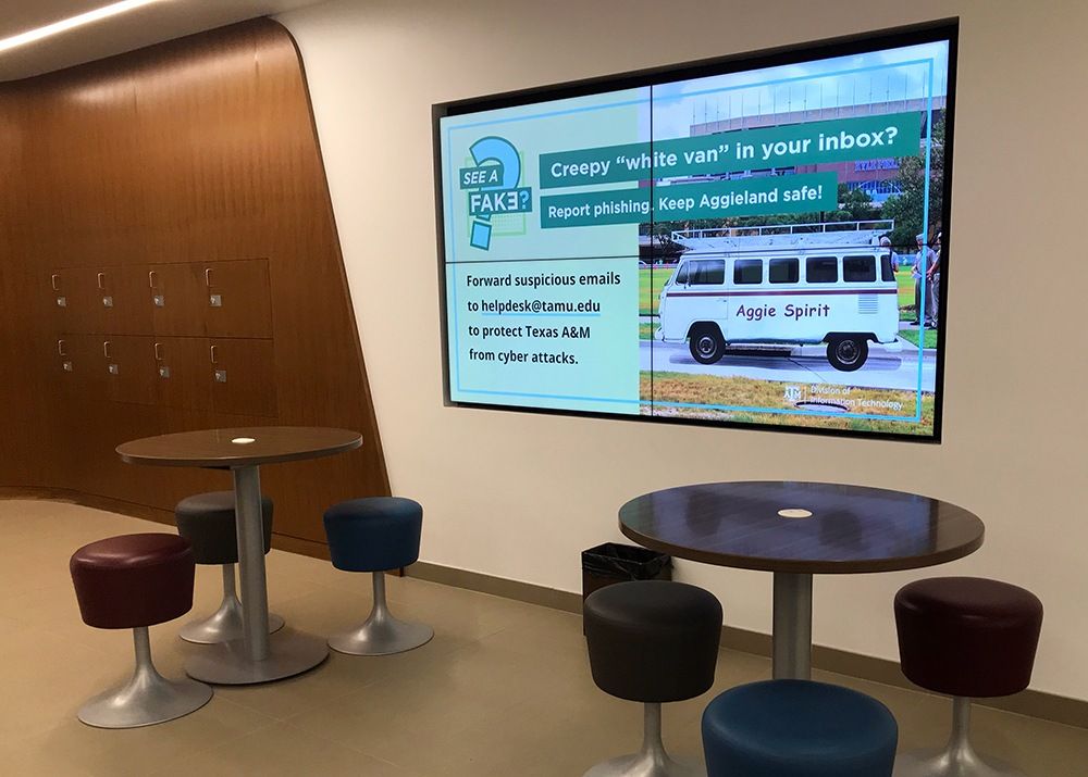 Large digital screen in Help Desk Central displays the "Creepy 'white van' in your inbox?' sign.